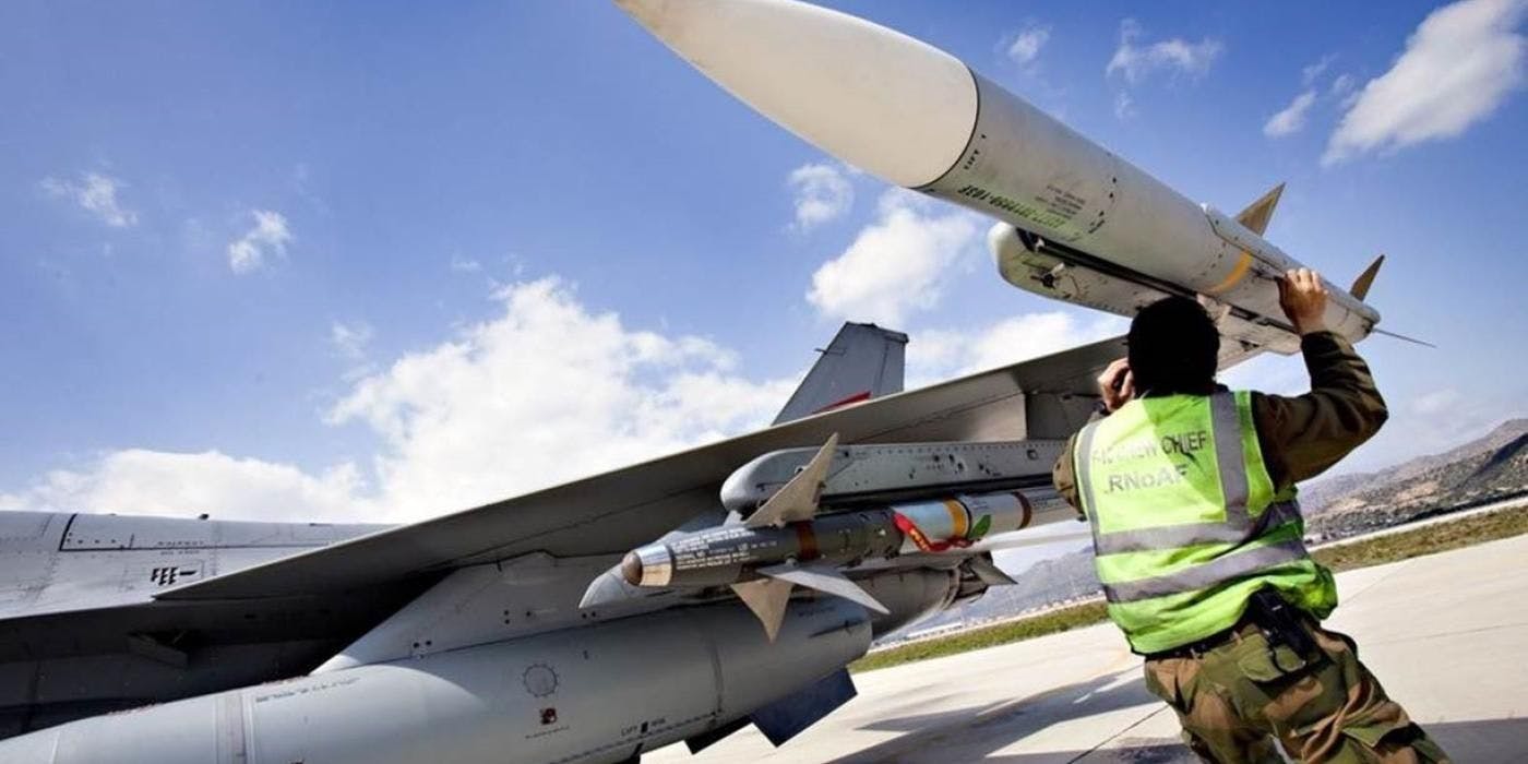 Bilde av en mann i uniform som holder i en rakett ytterst på vingen på et jagerfly.
